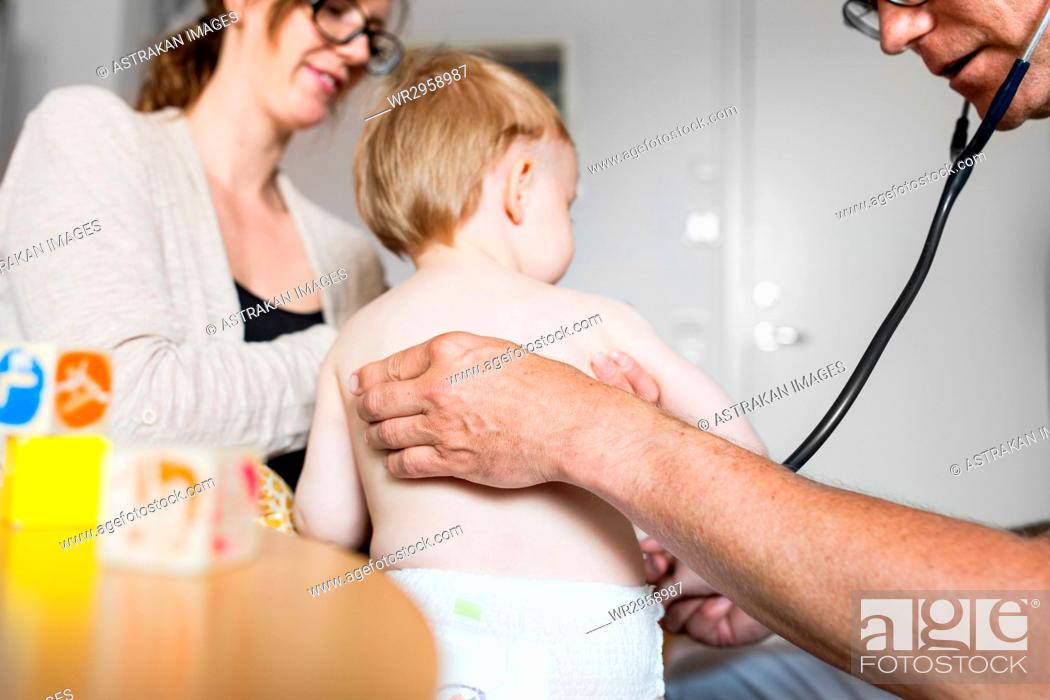 Stock Photo: Baby (12-17 months) with mother and doctor in examination room.