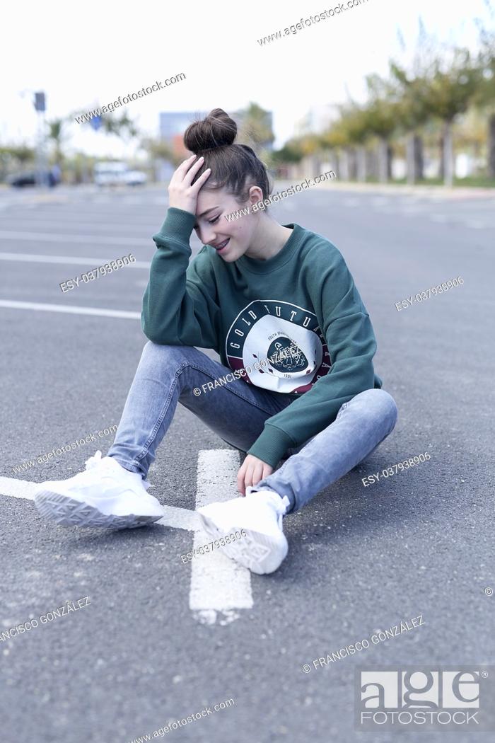 Stock Photo: Teen girl sitting on the floor of a parking garage. Vertical shot with natural light.
