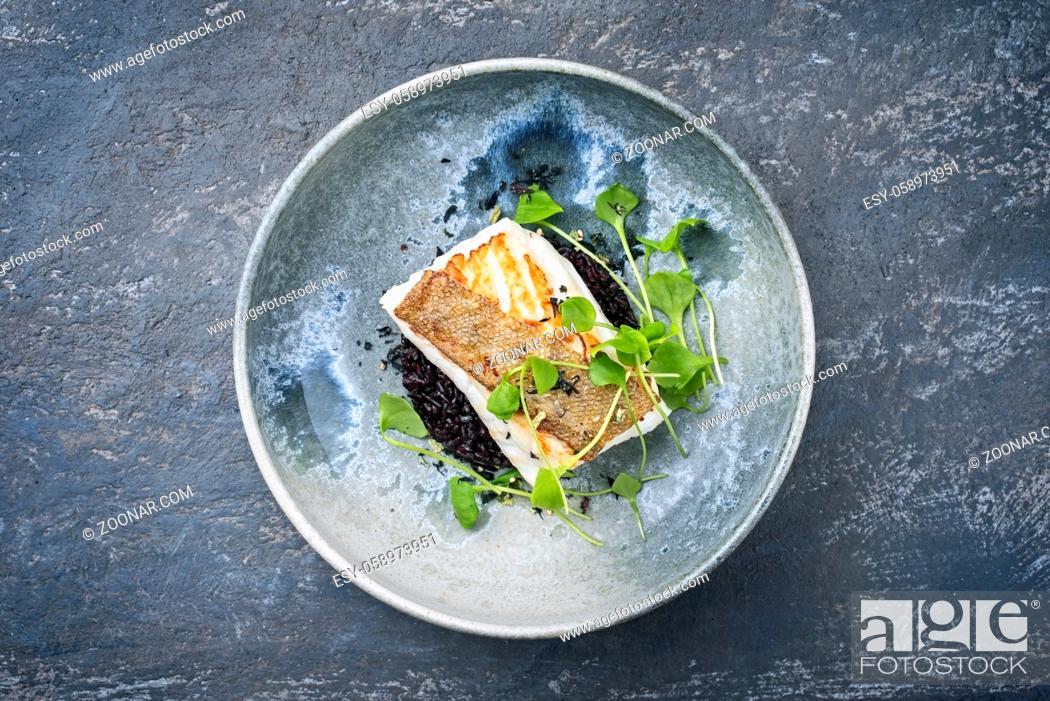 Stock Photo: Modern style traditional fried skrei cod fish filet with portulaca lettuce, and black rice served as top view on ceramic design plate with copy space.