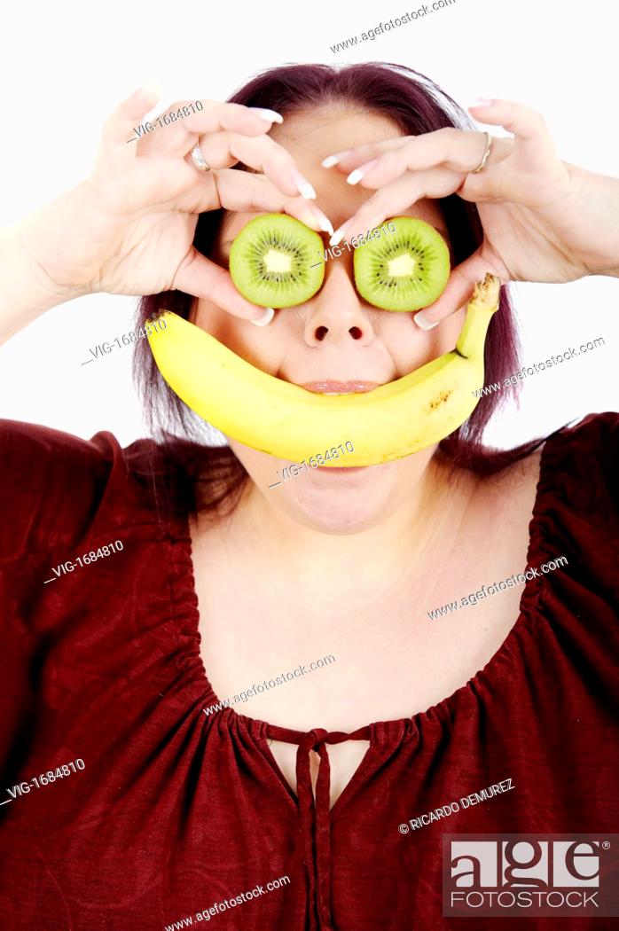 Stock Photo: AUSTRIA , VIENNA , 11.01.2009, Young fat woman with a banana in her mouth and kiwis in front of her eyes - Vienna, Vienna, AUSTRIA, 11/01/2009.
