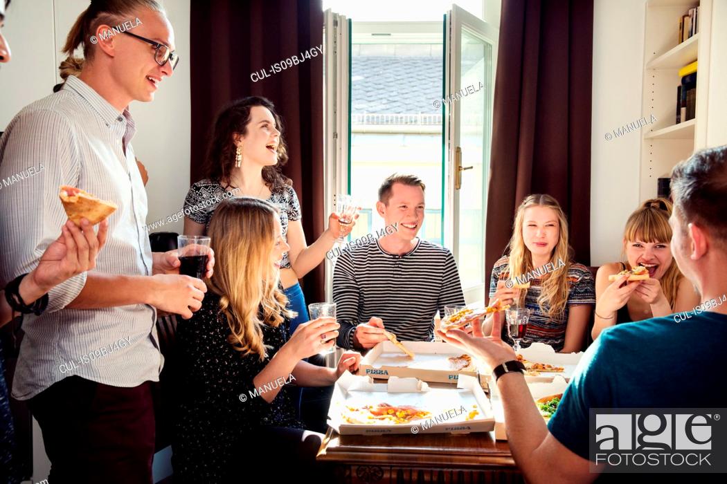 Stock Photo: Group of friends chatting over drinks and pizza at home.