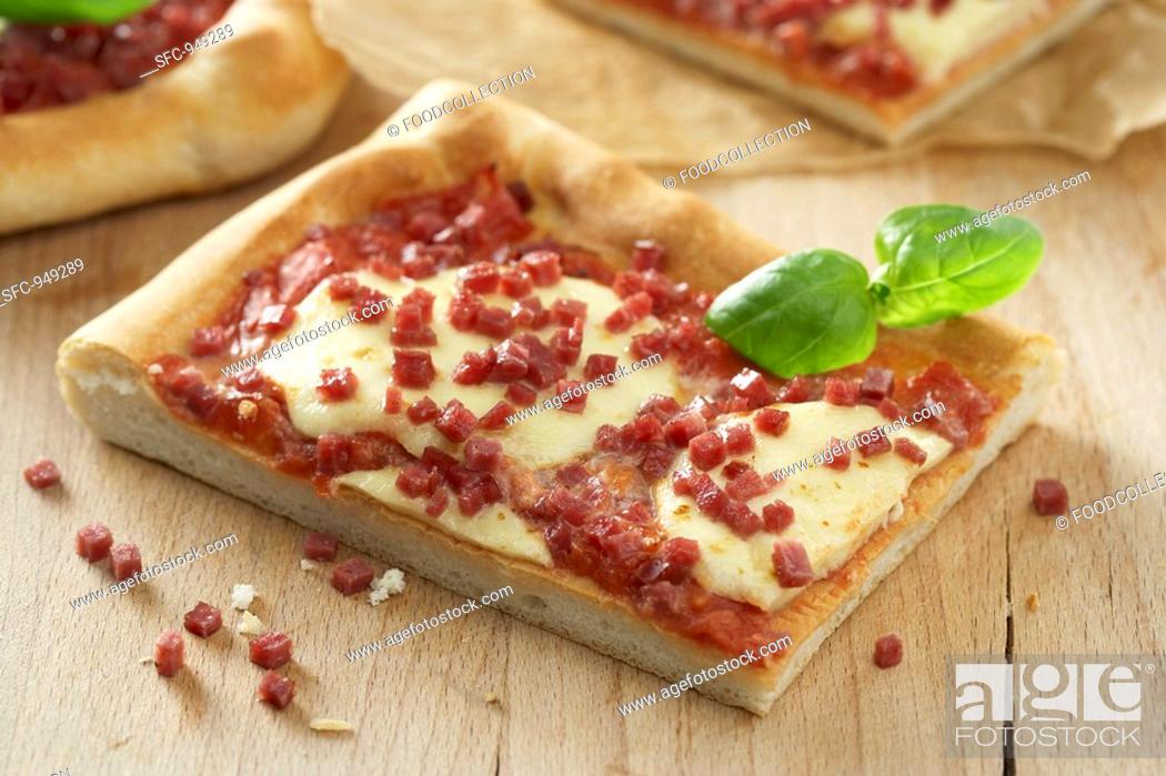 Stock Photo: Pieces of salami and mozzarella pizza with basil.