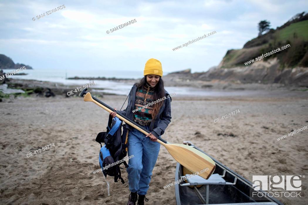 Stock Photo: Young woman with oars at canoe on winter beach.