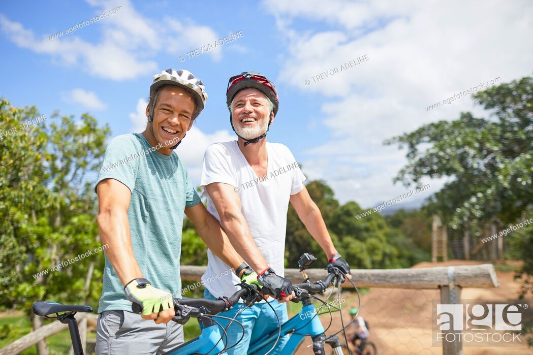 Stock Photo: Portrait confident father and son mountain biking on sunny trail.