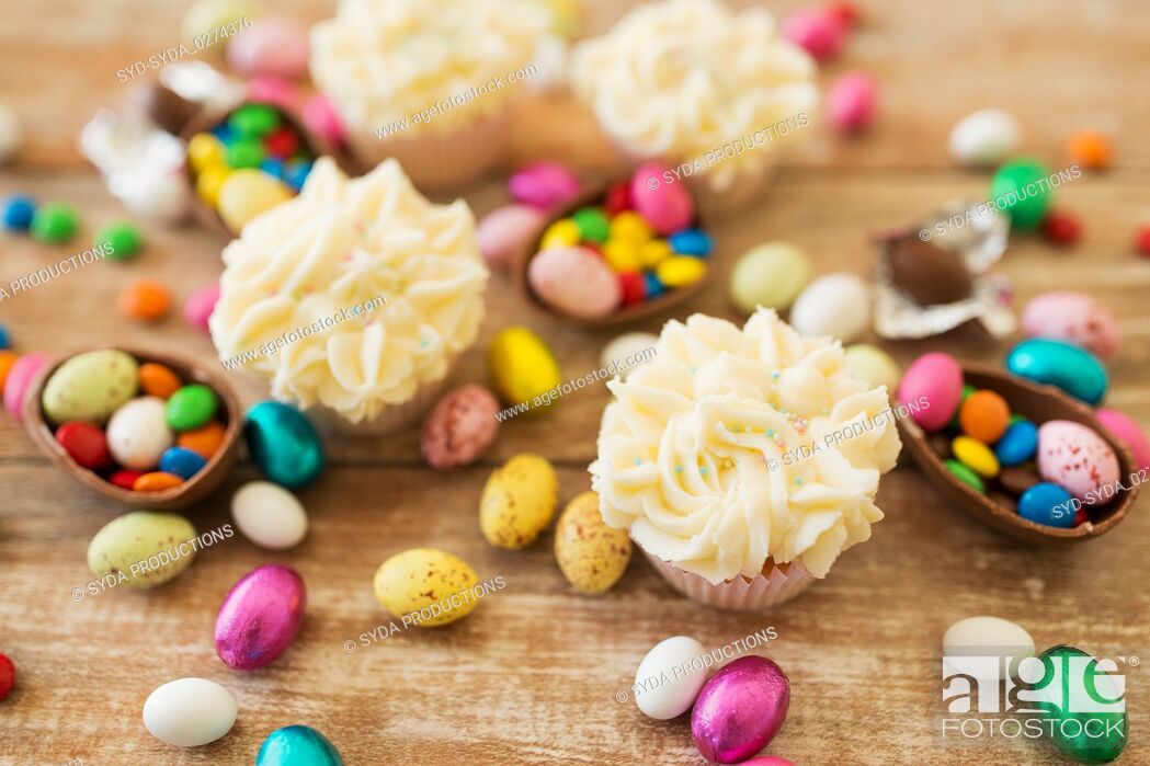 Stock Photo: cupcakes with chocolate eggs and candies on table.