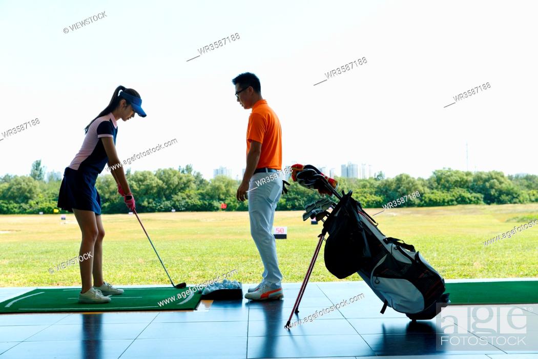 Stock Photo: The practice field of coaching young woman to play golf.