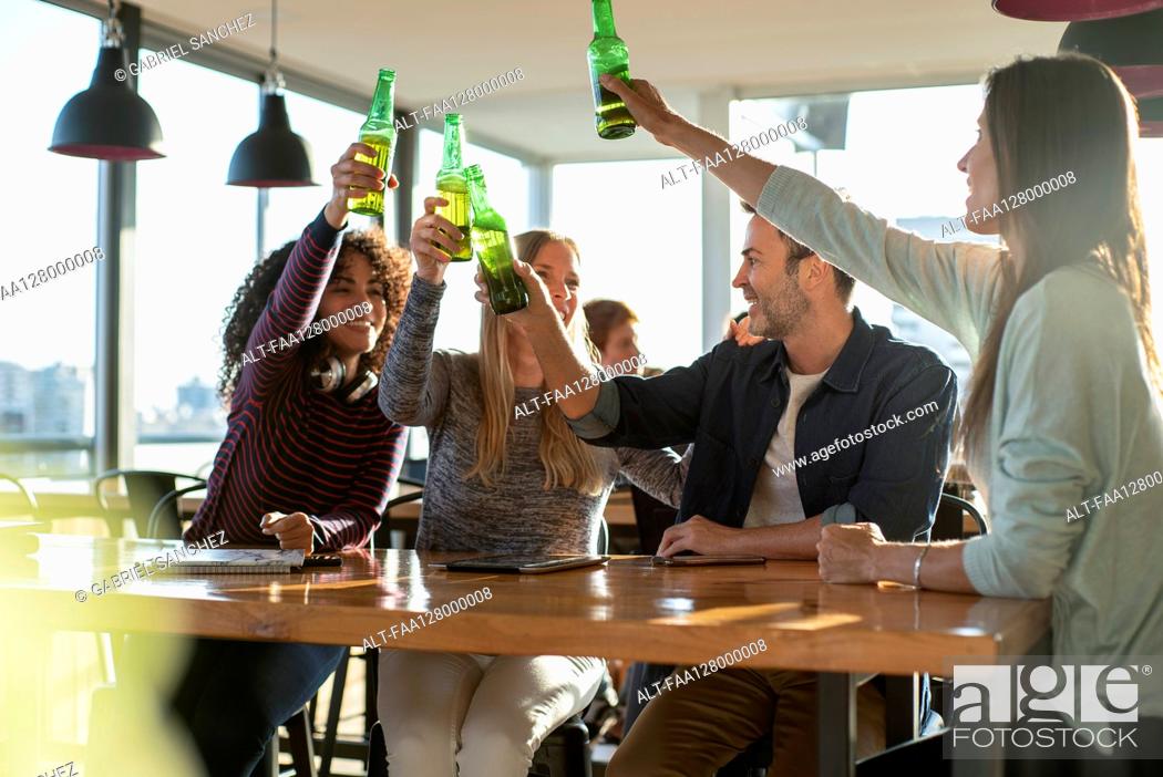 Photo de stock: Smiling colleagues toasting drink bottles in office.