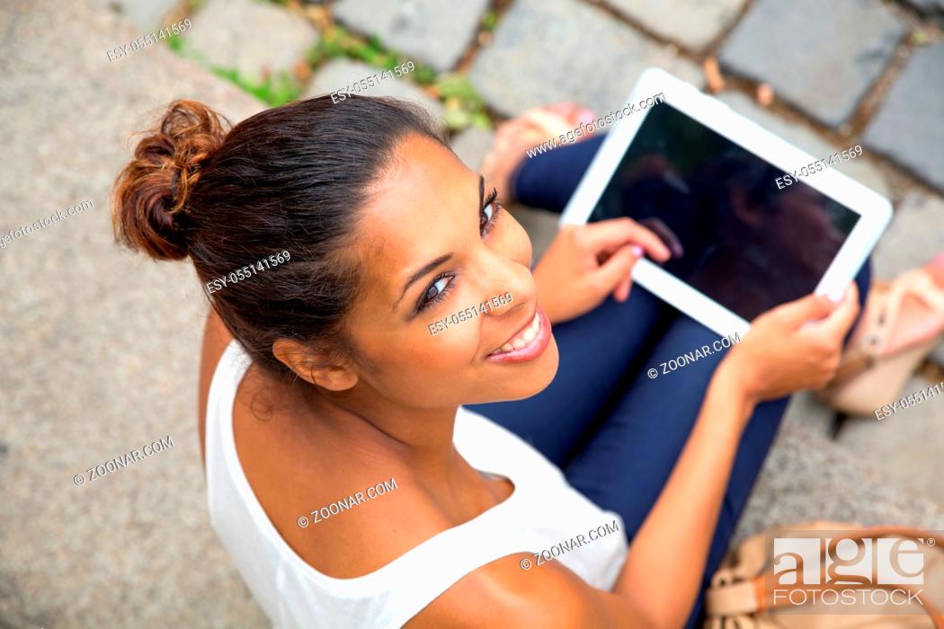Stock Photo: Hispanic girl using tablet in the city.