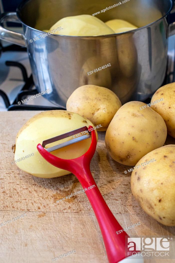 Stock Photo: Pile of potatoes being peeled and prepared for cooking in a pot.