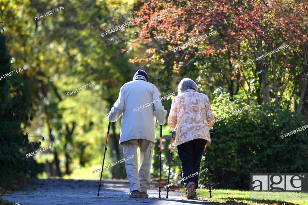 Stock Photo: Old married couple pensioner man and woman go for a walk with Nordic walking sticks. | usage worldwide. - Munich/Bayern/Deutschland.