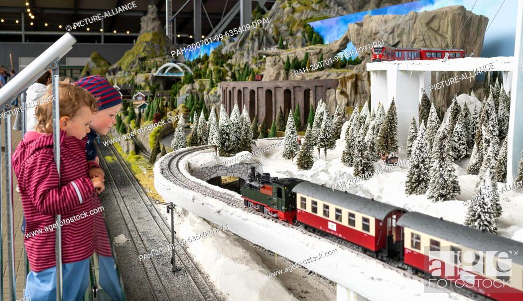 Stock Photo: 01 July 2020, Lower Saxony, Bispingen: Two children look at a passing train on the model railway layout. A total of 500 trains are to roll through various theme.