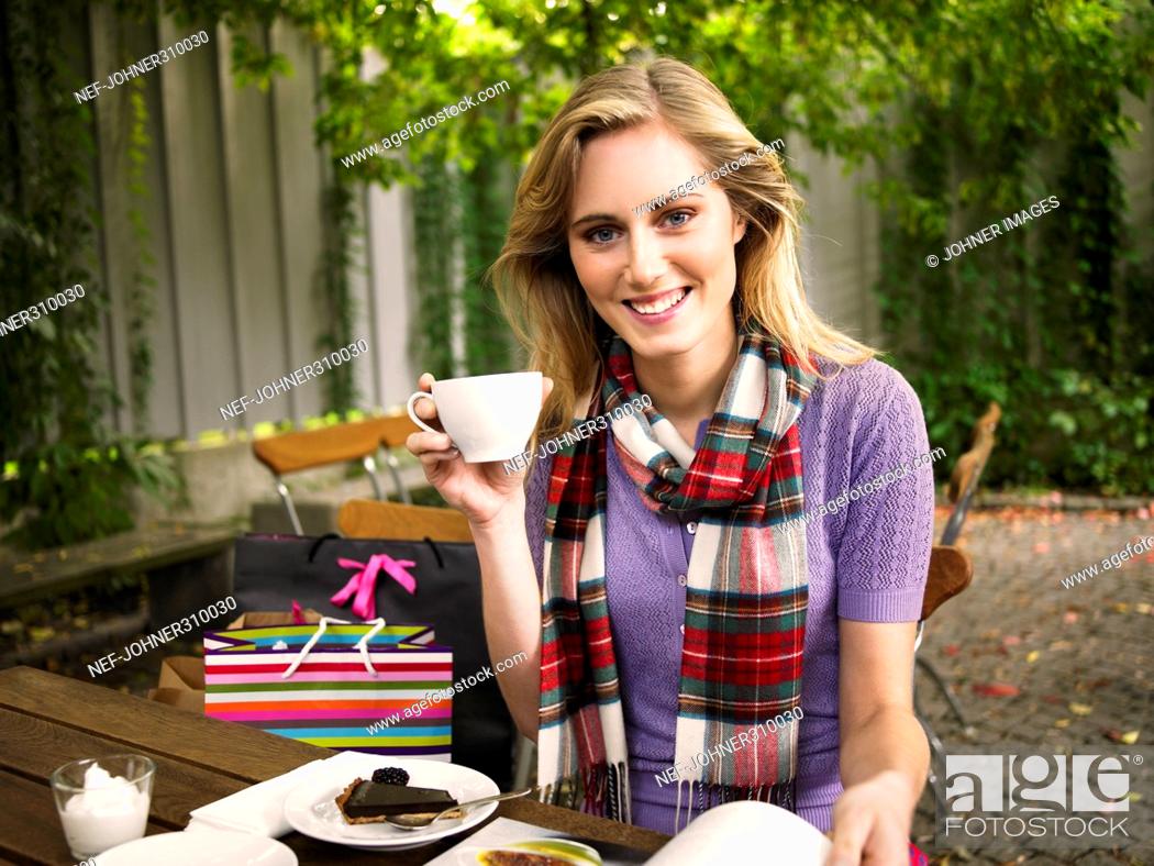 Stock Photo: A smiling young woman in a cafe outside.