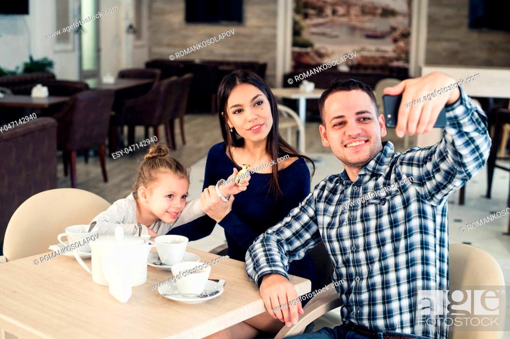 Stock Photo: family, parenthood, technology and people concept - happy mother, father and little girl having dinner and taking selfie by smartphone at restaurant.