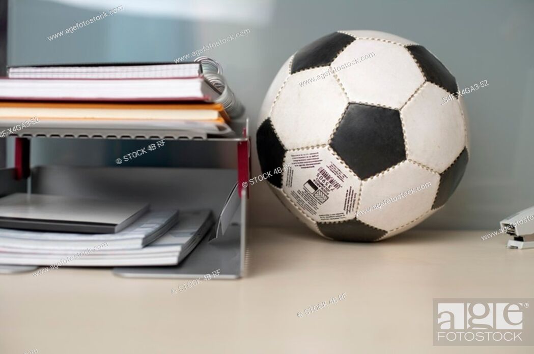 Stock Photo: Football on the desktop besides some documents.