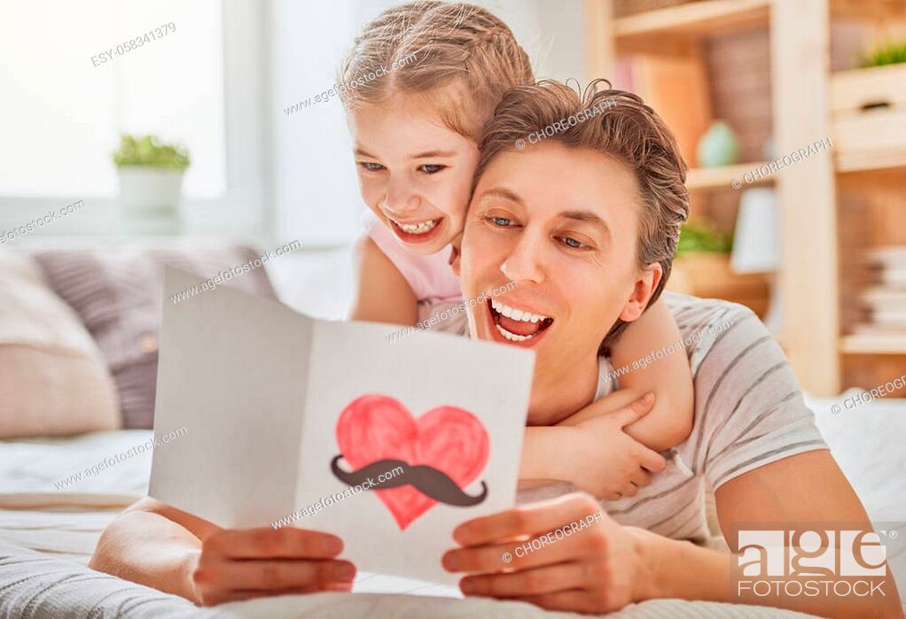 Stock Photo: Happy father's day! Child daughter congratulates dad and gives him postcard. Daddy and girl smiling and hugging. Family holiday and togetherness.