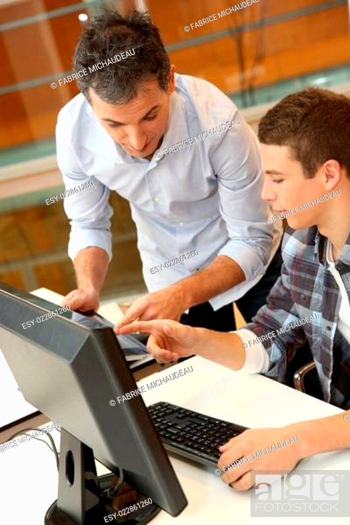 Stock Photo: Adult man helping student in classroom.