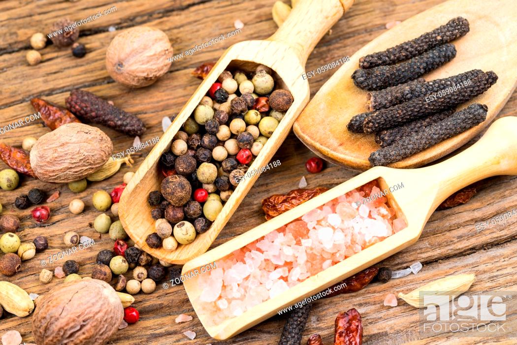 Stock Photo: Closeup of spice scoops and a wooden cooking spoon with various exotic spices and further spices in the background on a rustic wood background.