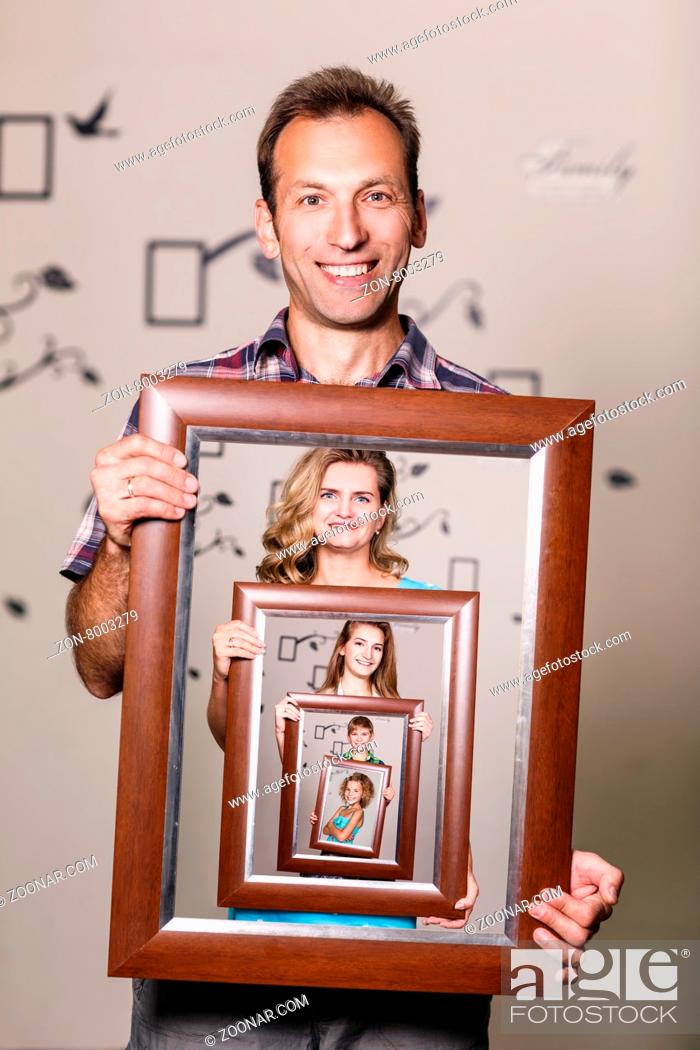 Stock Photo: Happy father holding portrait with his family each is located inside their own frame.