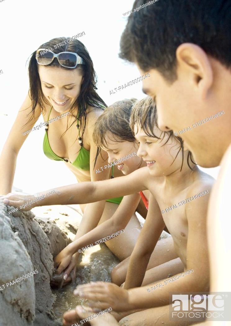 Imagen: Family playing in sand on beach together.