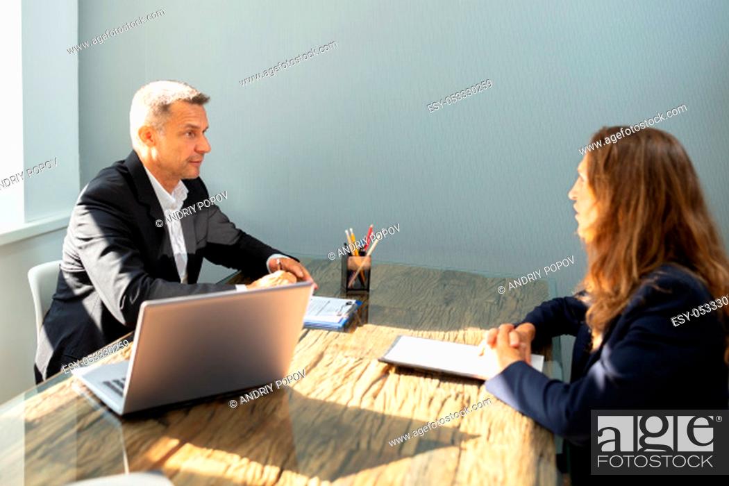 Stock Photo: Mature Businessman Taking An Interview Of Woman Over The Wooden Desk In Office.