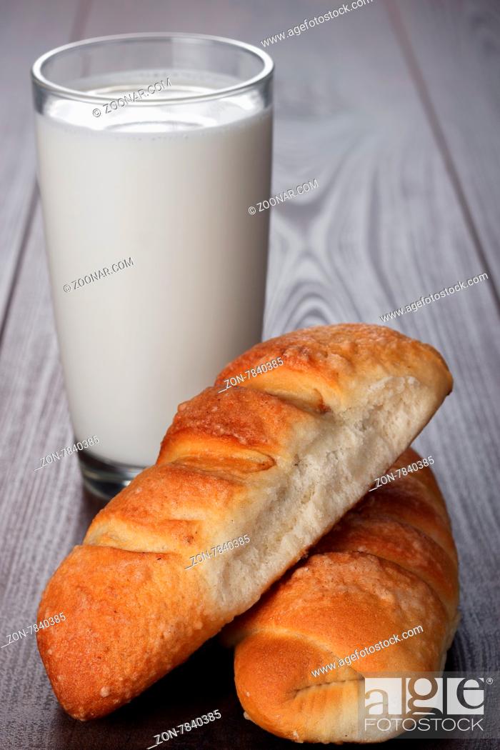 Stock Photo: glass of milk and fresh buns on the wooden table.