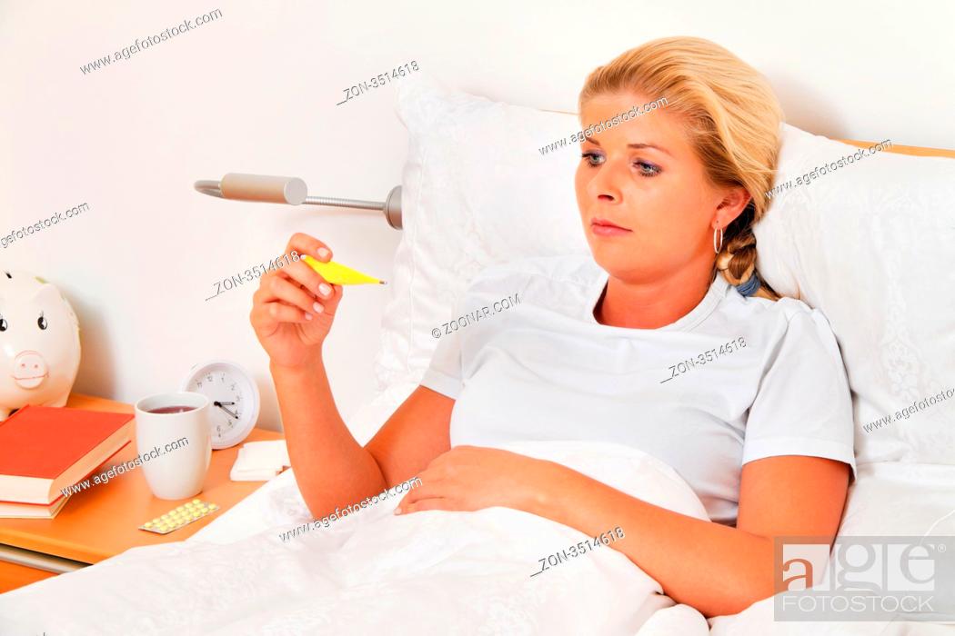 Photo de stock: Eine Frau im Bett ist Krank und hat Fieberthermometer.