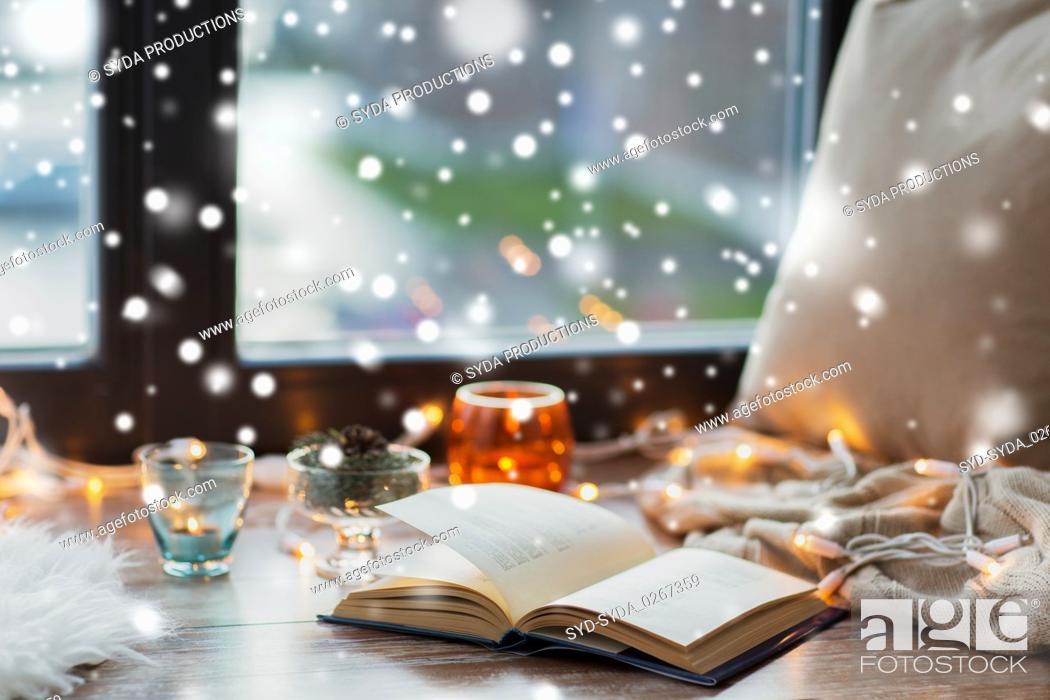 Stock Photo: book, garland lights and candles on window sill.