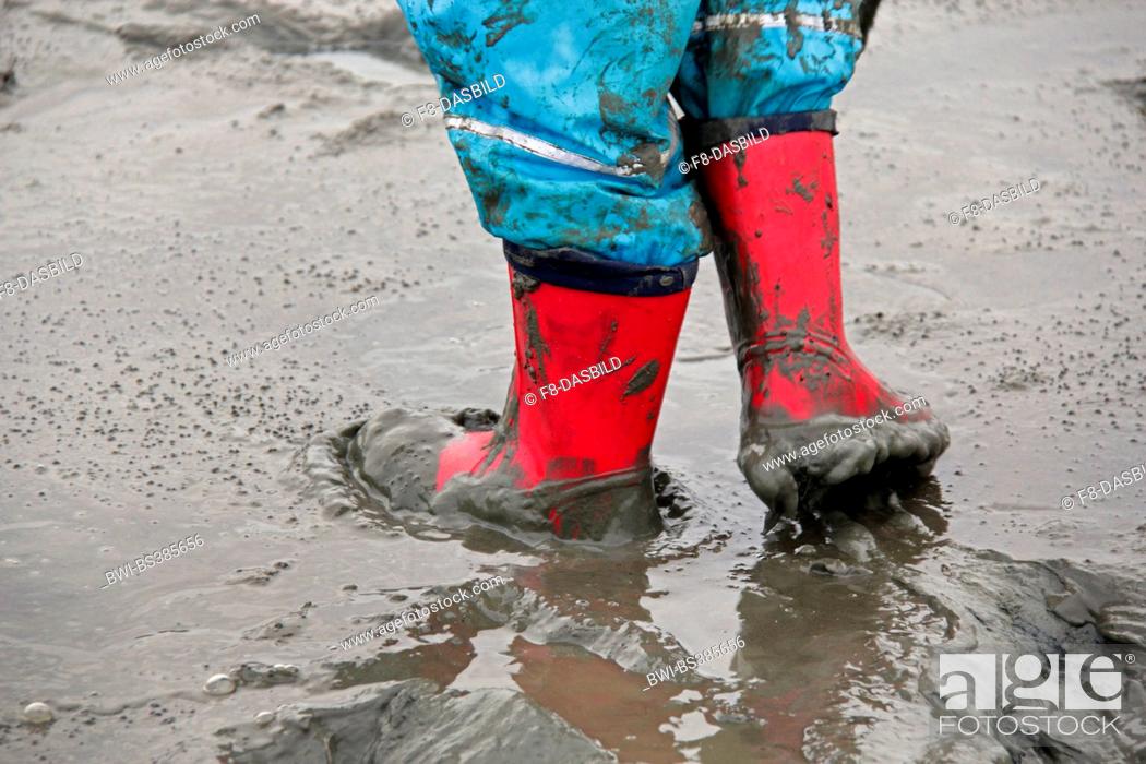 Photo de stock: child walking through the mud flat, waterproof pants and rubber boots, Germany, Lower Saxony, Cuxhaven.