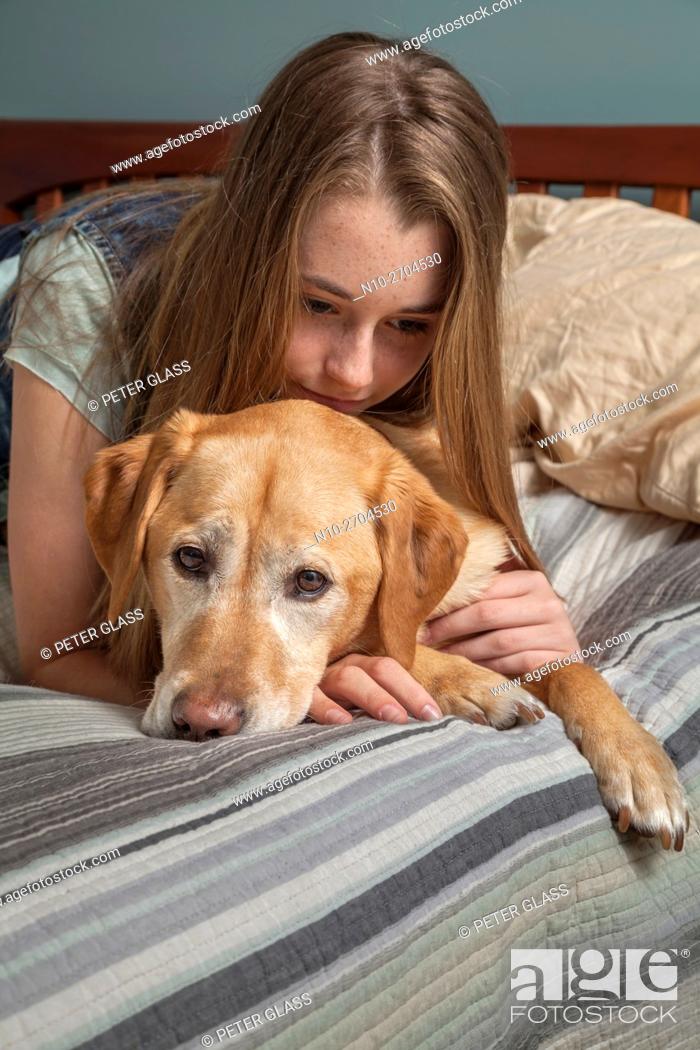Stock Photo: Teenage girl with her pet dog, on her bed.