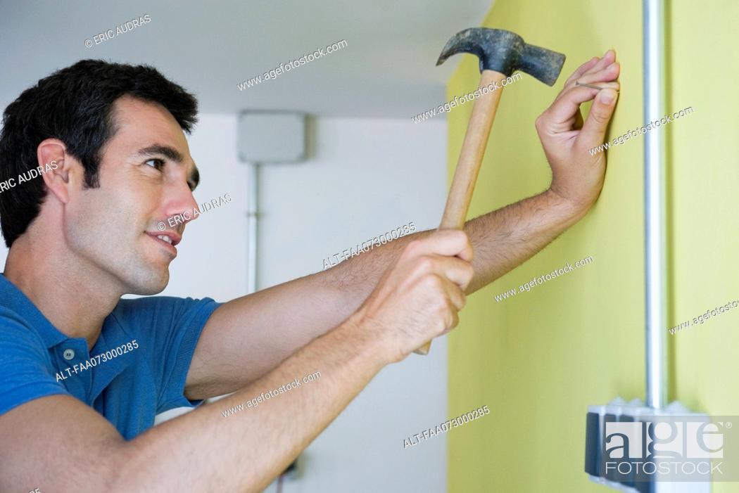Man hammering nail into wall, Stock Photo, Picture And Royalty Free Image.  Pic. ALT-FAA073000285 | agefotostock