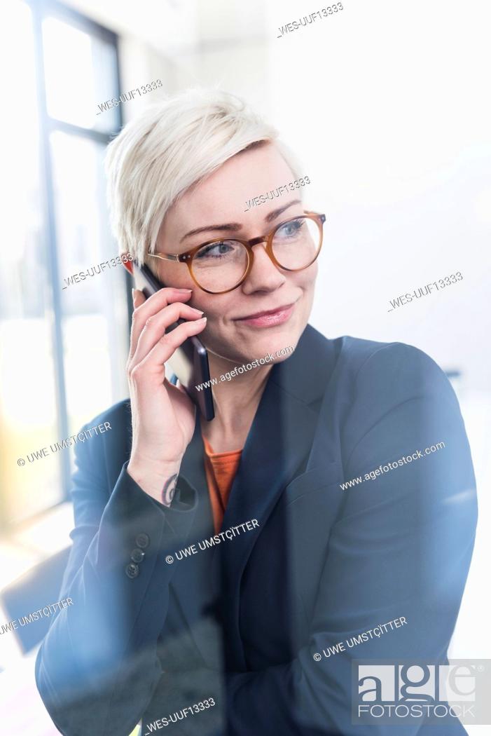Stock Photo: Portrait of confident businesswoman on cell phone in office.