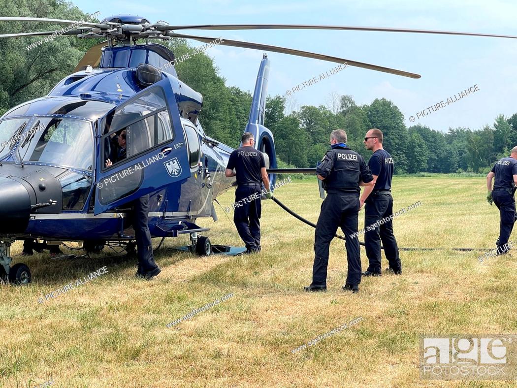 Stock Photo: 19 June 2021, Brandenburg, Oberkrämer: Police officers stand by a helicopter. In the largest forest fire so far since the beginning of the season.