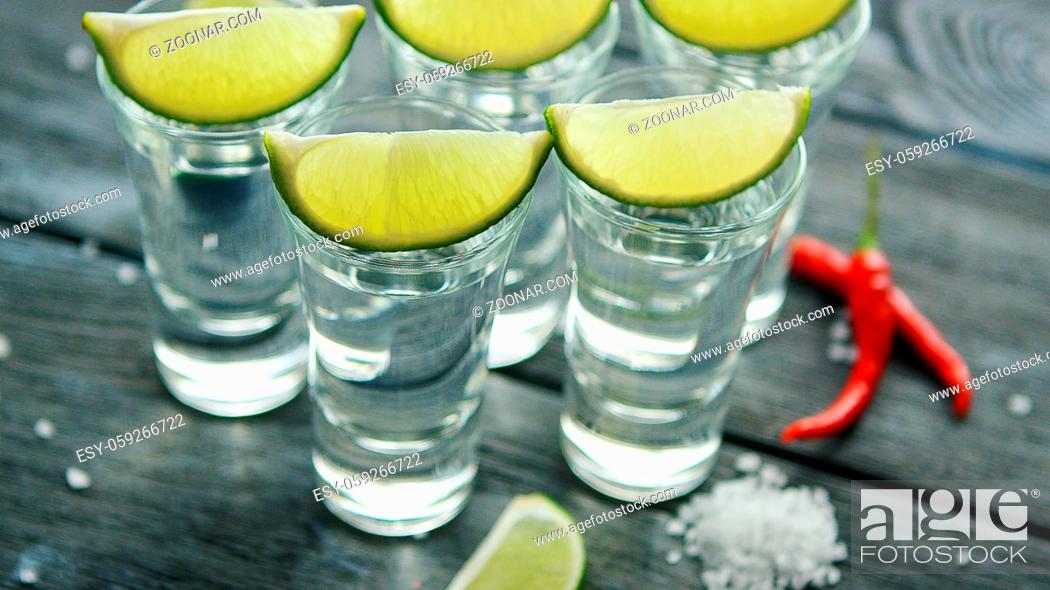 Stock Photo: From above tequila shots served with lime and salt on wooden table with pepper.