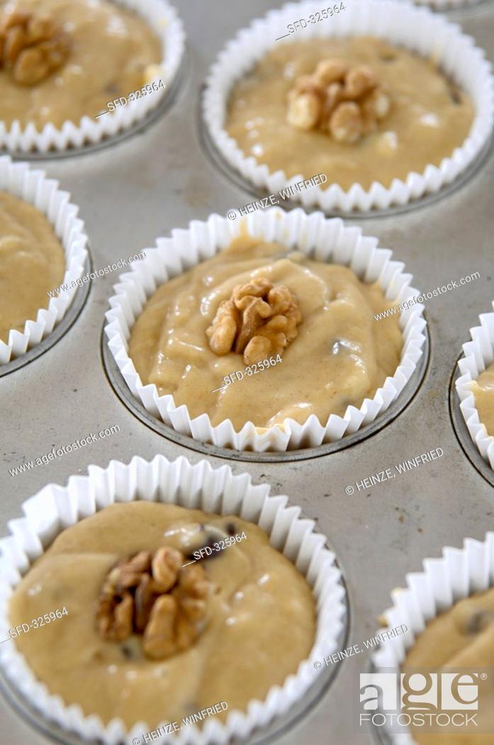 Stock Photo: Banana & chocolate muffin mixture with walnuts in muffin tin.