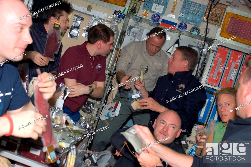 Stock Photo: Eight of ten astronauts and cosmonauts currently sharing work on the International Space Station share a mealtime on the Zvezda service module.