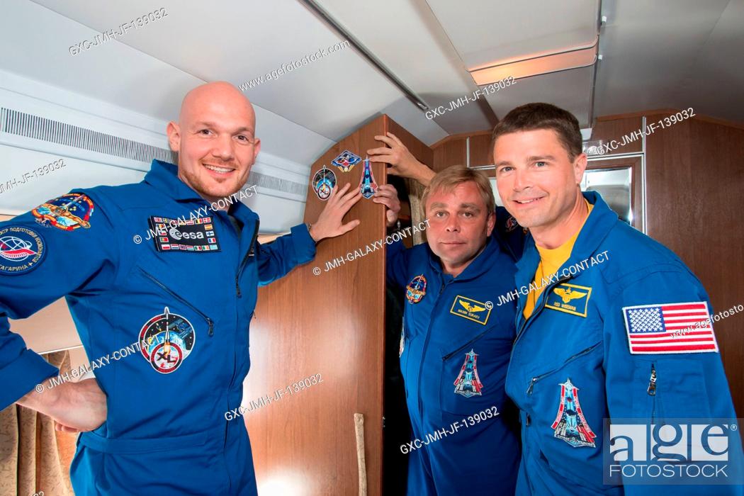 Stock Photo: Keeping with tradition, the Expedition 4041 crew members affix the stickers bearing their crew insignias to the cabin of the plane that carried them May 15 to.