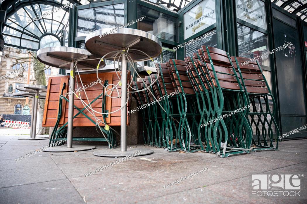 Stock Photo: 18 May 2021, Hamburg: Tables and chairs are stacked up in front of a café in the city centre. In view of the low Corona figures.