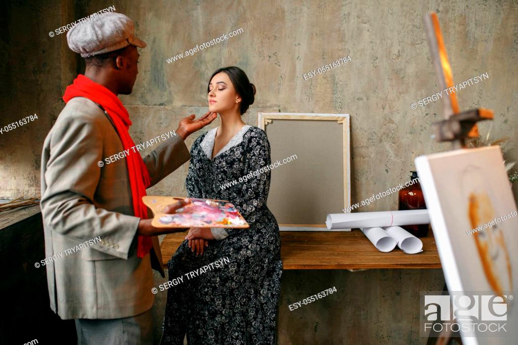 Stock Photo: Portrait painter prepares female model in art studio. Male artist standing at his workplace, creative master in workshop.