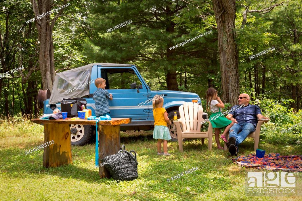 Stock Photo: Father and children sitting in woods beside off road vehicle.