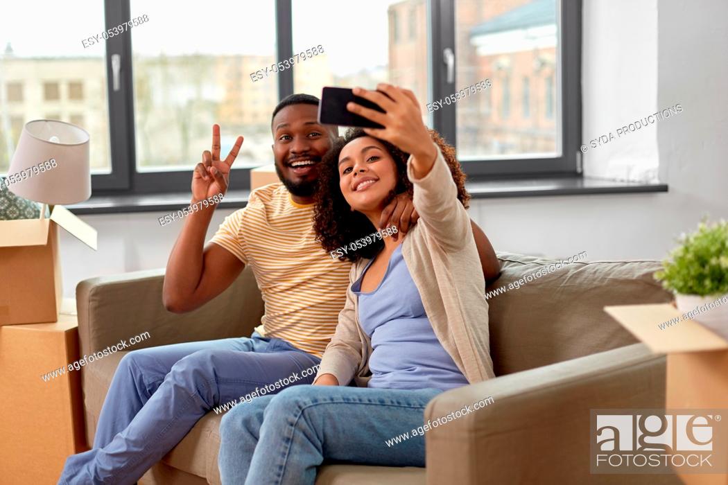 Stock Photo: happy couple moving to new home and taking selfie.