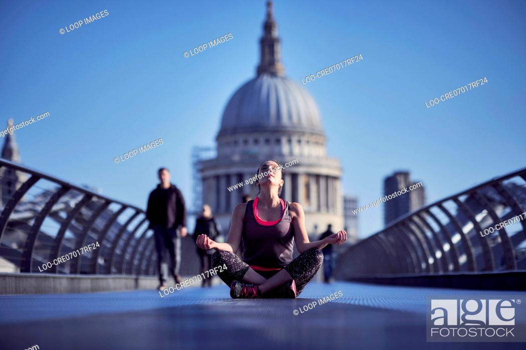 Photo de stock: A woman meditating on the Millennium Bridge with St Paul's Cathedral in the background.