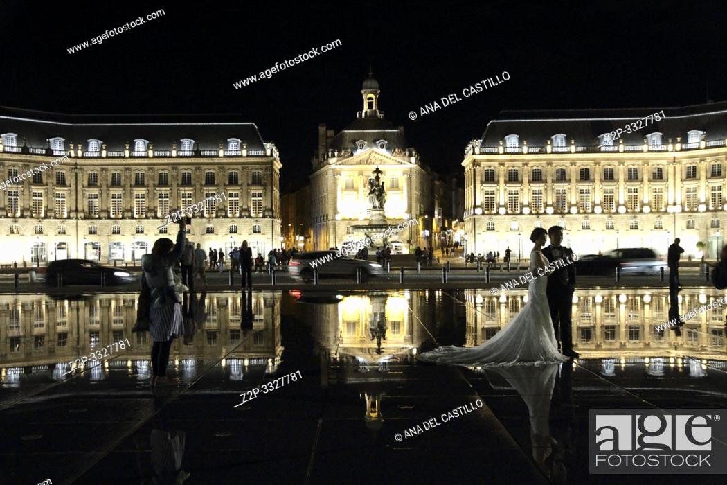 Stock Photo: Square of the Bourse by night on September 4, 2015 in Bordeaux, Aquitaine, France. Wedding photographer in action, taking a picture of the bride and groom.