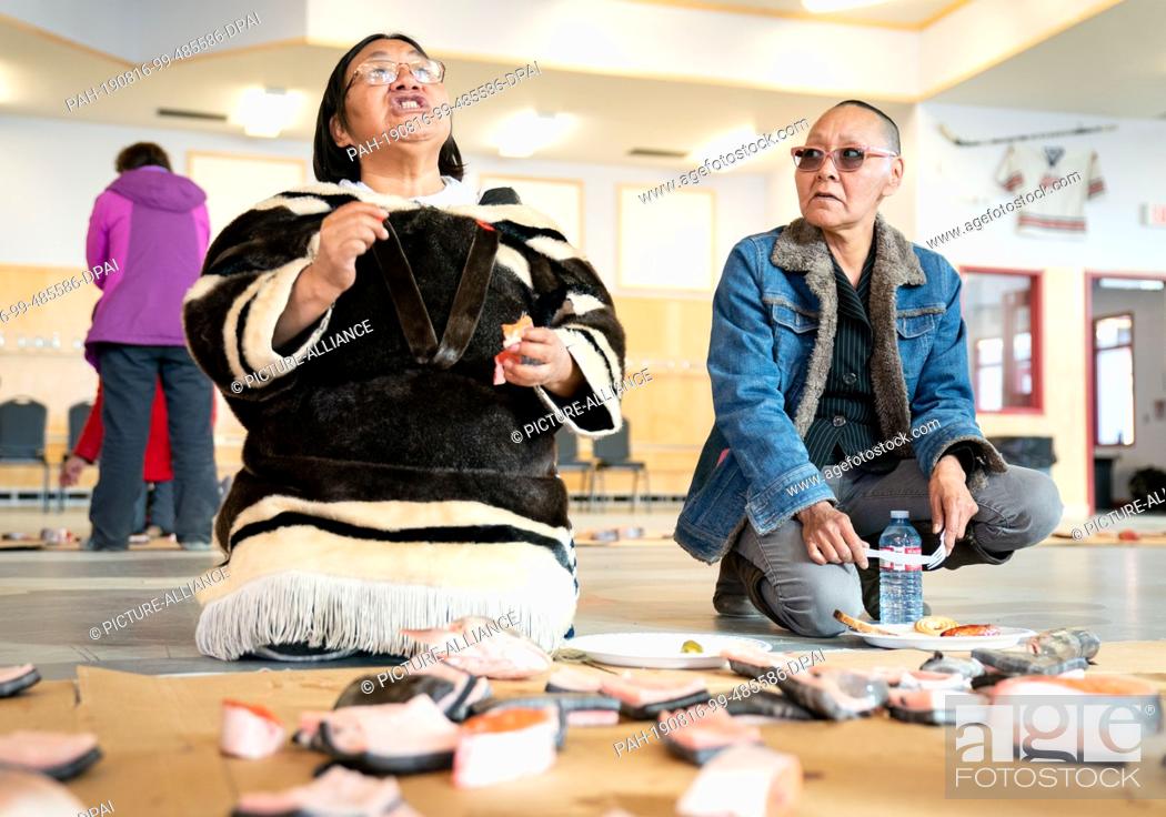 Stock Photo: 15 August 2019, Canada, Pond Inlet: Inuits eat raw fish and whale meat in a hall in the town of Pond Inlet, in the Canadian Arctic.