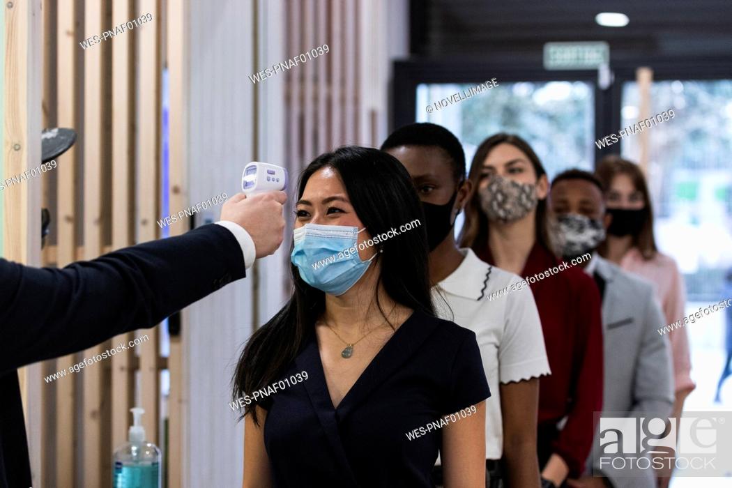 Stock Photo: Employees with face mask going through temperature checkpoint at office.