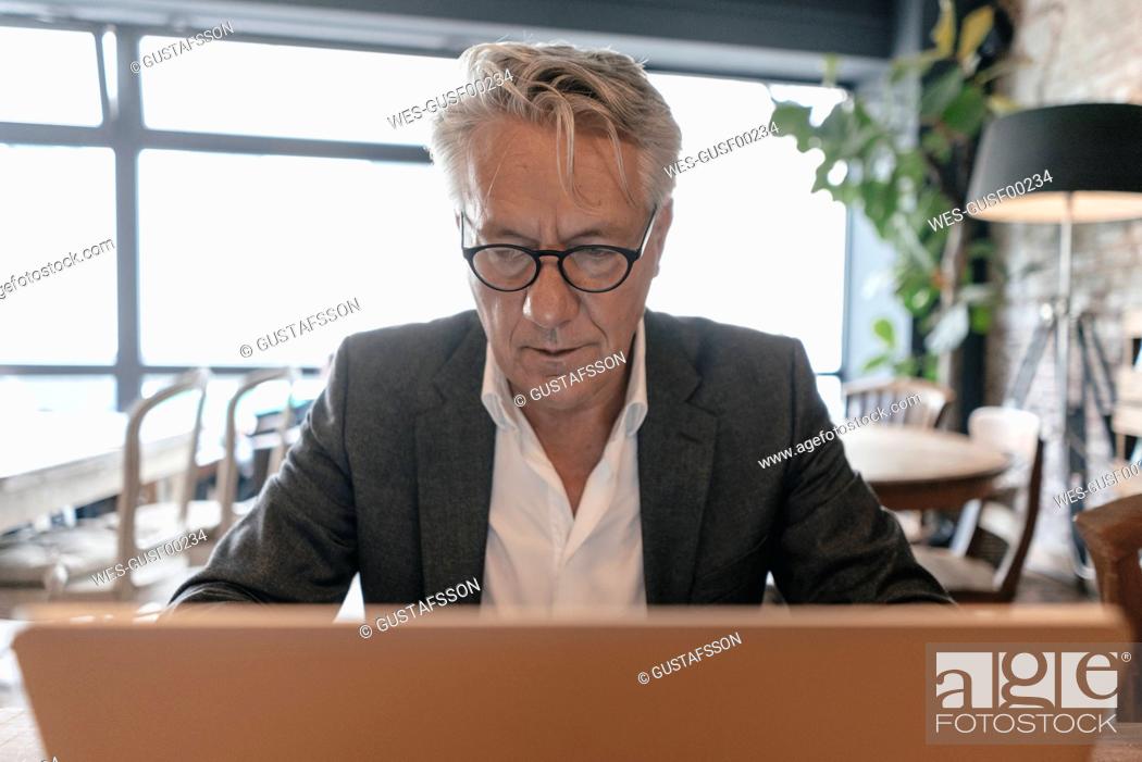 Stock Photo: Senior businessman sitting in a cafe, using laptop.