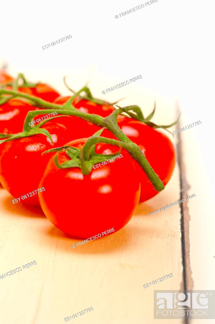 Stock Photo: fresh cherry tomatoes on a cluster over rustic wood table.