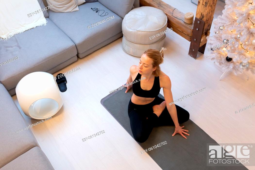 Stock Photo: Beautiful blonde woman doing home workout indoors. Woman practice yoga at home. Fit girl using workout tutorials for healthy active lifestyle.