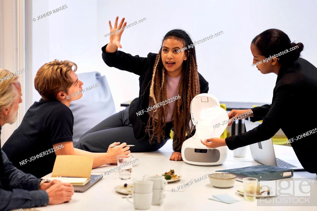 Stock Photo: Business people discussing robot voice assistant during meeting.