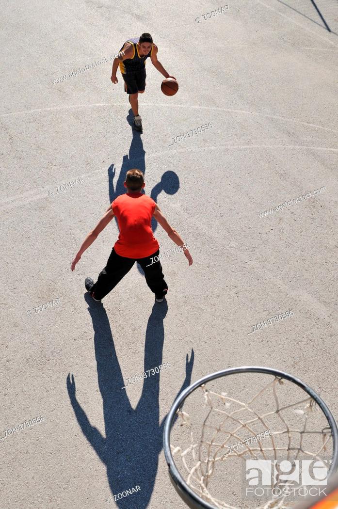 Stock Photo: gorup of young boys who playing basketball outdoor on street with long shadows and bird view perspective.