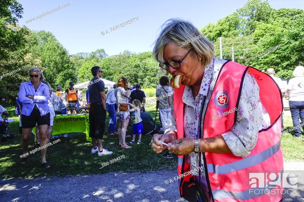 Stock Photo: A woman multitasking with a hotdog in her mouth in the Nacka suburb where locals hold a protest about how rainwater is runoff into a local lake demanding.